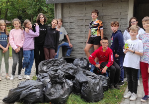 uczniowie klasy 7 b pozują do grupowego zdjęcia wraz z zebranymi w ramach akcji sprzątanie świata odpadami
