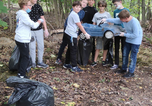 uczniowie klasy 6 b zbierają śmieci w lesie