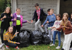 uczniowie klasy 5 b pozują do grupowego zdjęcia wraz z zebranymi w ramach akcji sprzątanie świata odpadami